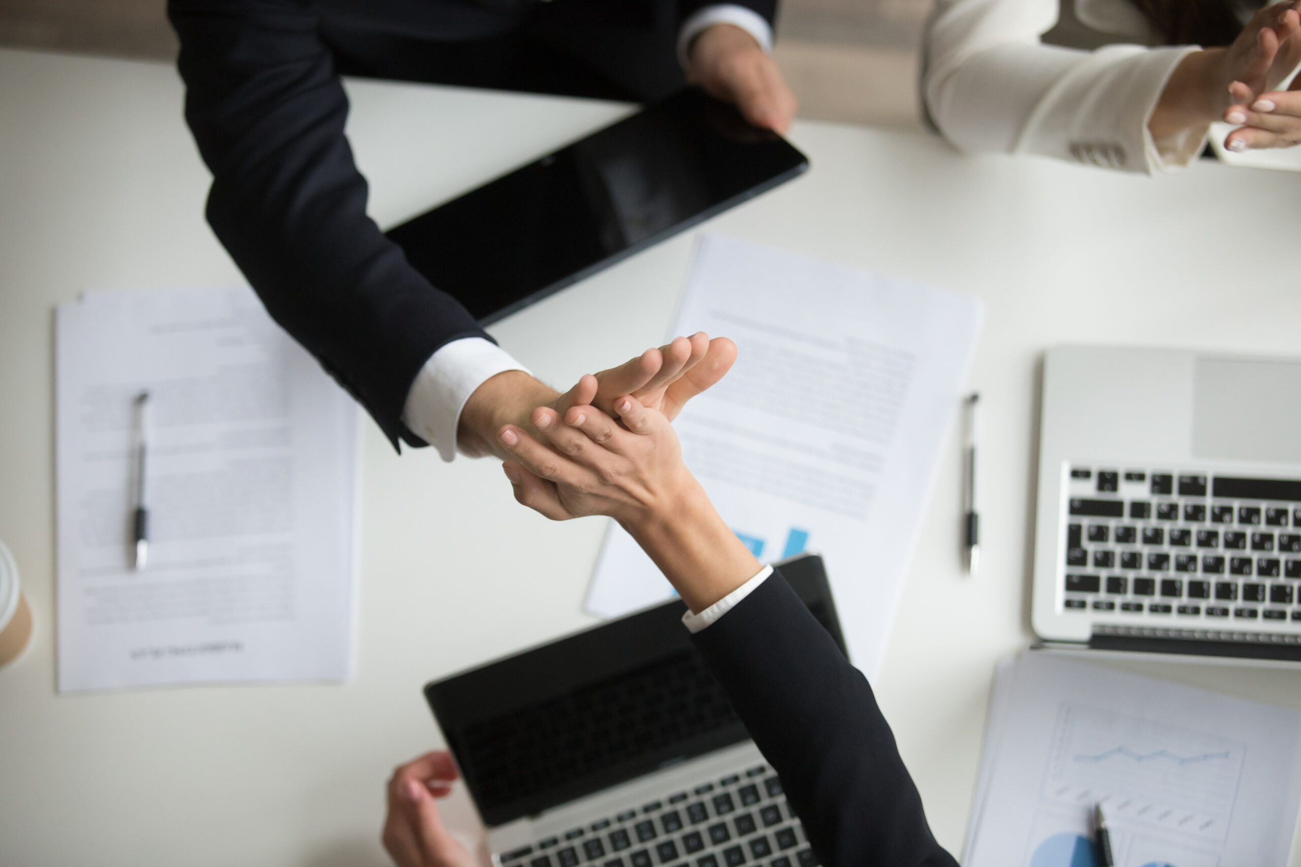 Colleagues giving high five above office desk celebrating good teamwork result or victory, motivated coworkers team join hands sharing business success, great collaboration concept, top close up view